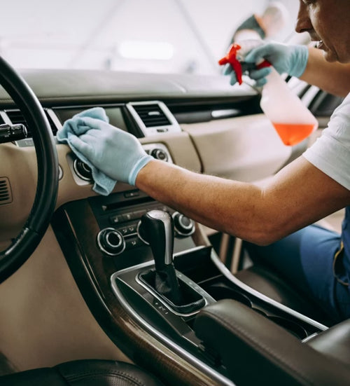 Person cleaning the interior of a car with gloves on